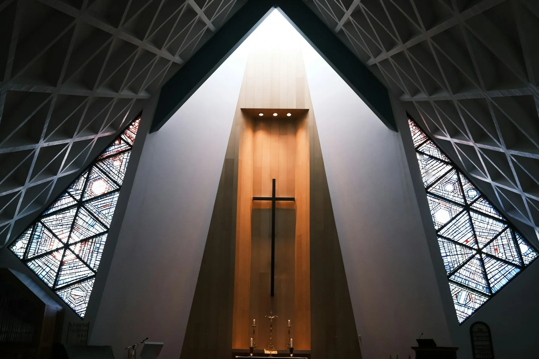 Contemporary sanctuary interior with a vaulted ceiling and stained-glass windows